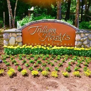 Shrubs planted in fron of apartment complex sign.