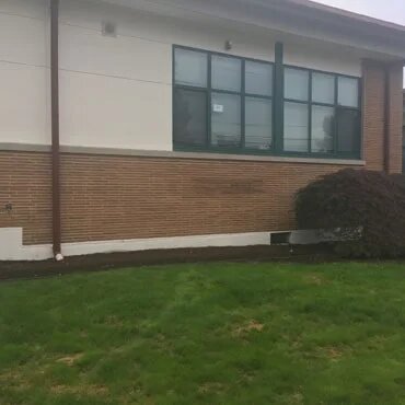 Paver border planting infront of school building before picture.